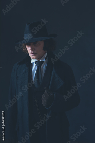 Mysterious victorian man in black coat and hat.