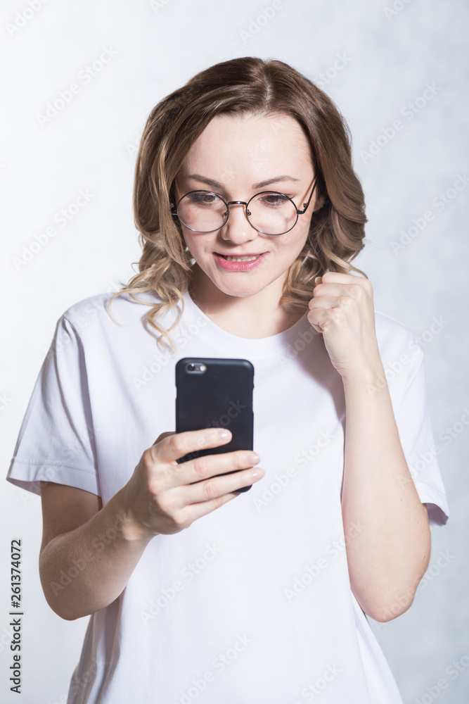 Perplexed and worried, a beautiful young woman is holding a smartphone, stares with surprised expression. Perplexed and worried, a beautiful young woman is holding a smartphone, stares with surprised expression.
