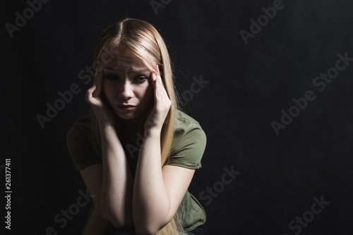 Sad young woman going to cry in a black background