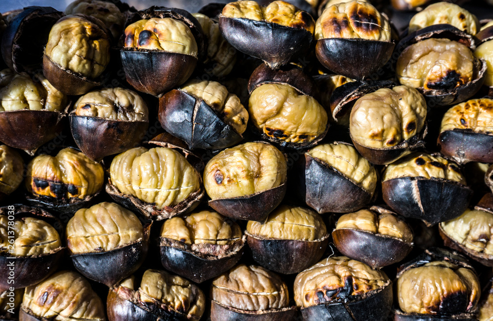 Fried chestnuts on street. Traditional street food in winter fire. Roasted chestnut background. Nutrition, agriculture, harvest concept. Bunch of hot fresh delicious grilled chestnuts at street vendor Fried chestnuts on street. Traditional street food in winter fire. Roasted chestnut background. Nutrition, agriculture, harvest concept. Bunch of hot fresh delicious grilled chestnuts at street vendor