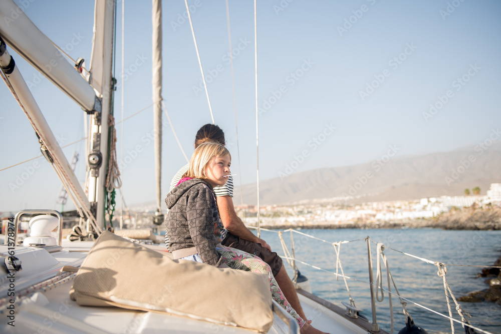 Side view of father with kids sitting on side deck of expensive boat floating on water in sunny day Side view of father with kids sitting on side deck of expensive boat floating on water in sunny day