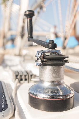 Winch with handle for hoisting rope on boat in sunny day on blurred background photo