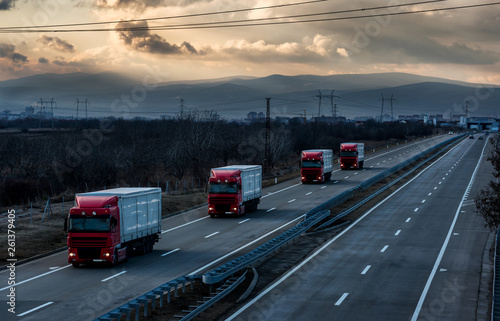 Caravan or convoy of lorry trucks on country highway under a beautiful sky
