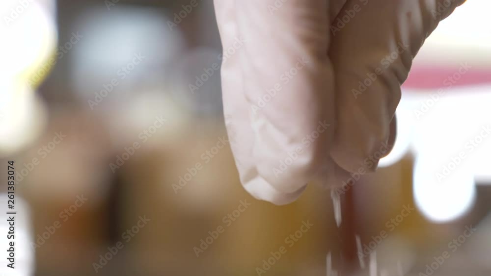 A Gloved Hand Sprinkling Salt in a Commercial Kitchen, Extreme Close Up, Slow Motion A Gloved Hand Sprinkling Salt in a Commercial Kitchen, Extreme Close Up, Slow Motion