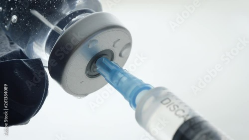 Extreme closeup of filling a syringe from a vaccine bottle. Mandatory vaccinations are currently a hotly debated topic with anti-vaxxers. Causing global outbreaks of preventable diseases like measles. photo