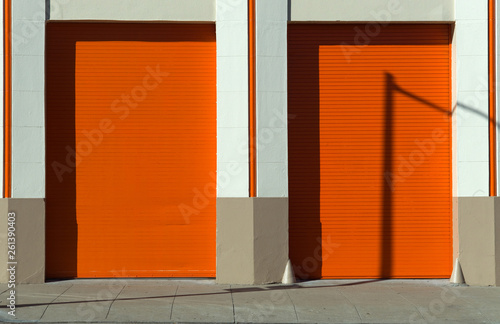 Orange doors and garage with masonery frame and wall sidewalk