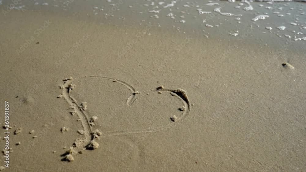 Heart drawing on the sand of the sea coast washes away by the sea wave Heart drawing on the sand of the sea coast washes away by the sea wave