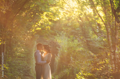 young couple hugging against the background of the forest and su
