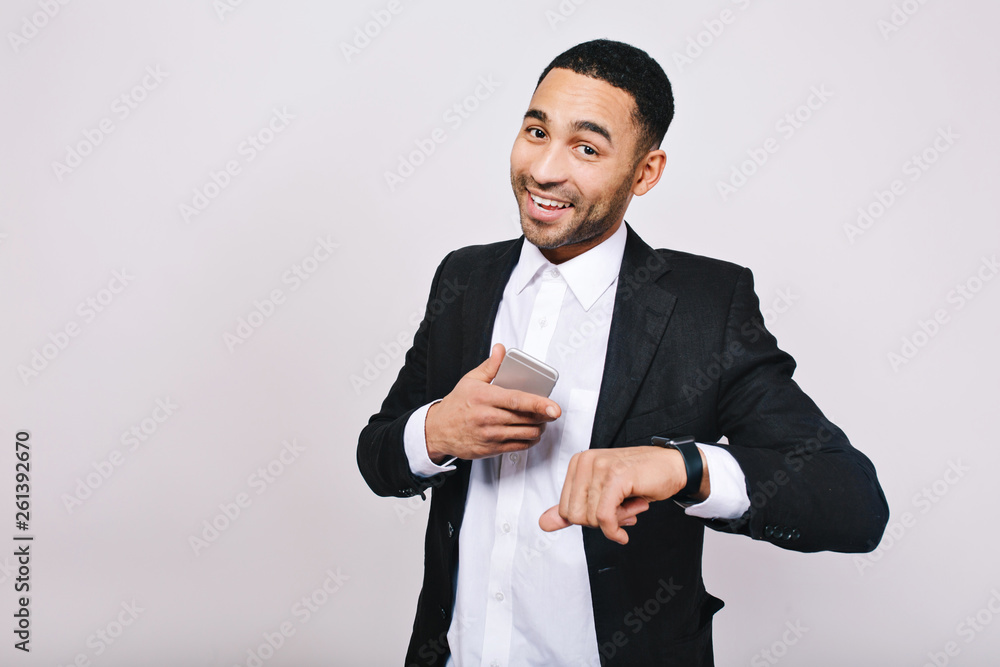 Great success, good resultas in career of handsome young man in white shirt, black jacket smiling to camera with phone on white background. Stylish businessman, smiling. Place for text Great success, good resultas in career of handsome young man in white shirt, black jacket smiling to camera with phone on white background. Stylish businessman, smiling. Place for text