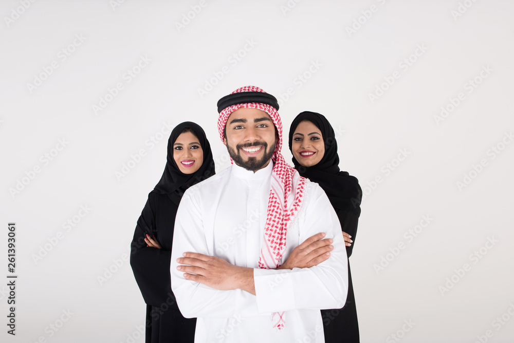 Two arab females with one male smiling and standing on white background Two arab females with one male smiling and standing on white background