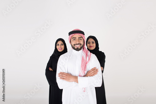 Two arab females with one male smiling and standing on white background