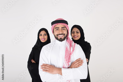 Two arab females with one male smiling and standing on white background