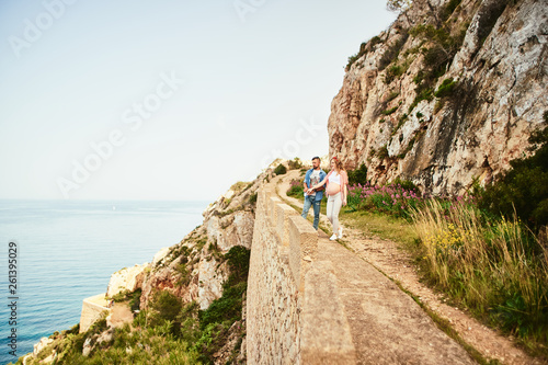 Young pregnant woman walking with her husband against sea background