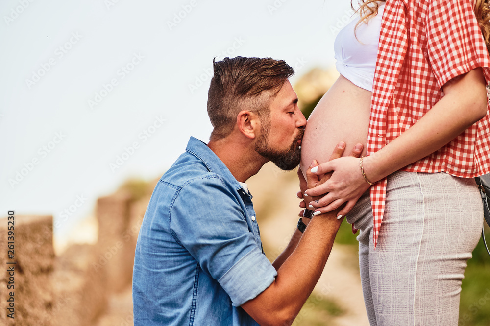 Fototapeta premium Young man kissing his pregnant wife's belly