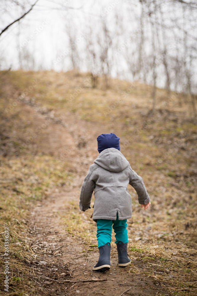 View from the back of a fashionable boy walking uphill on a cloudy spring or autumn day. Studies the area, learns new. View from the back of a fashionable boy walking uphill on a cloudy spring or autumn day. Studies the area, learns new.