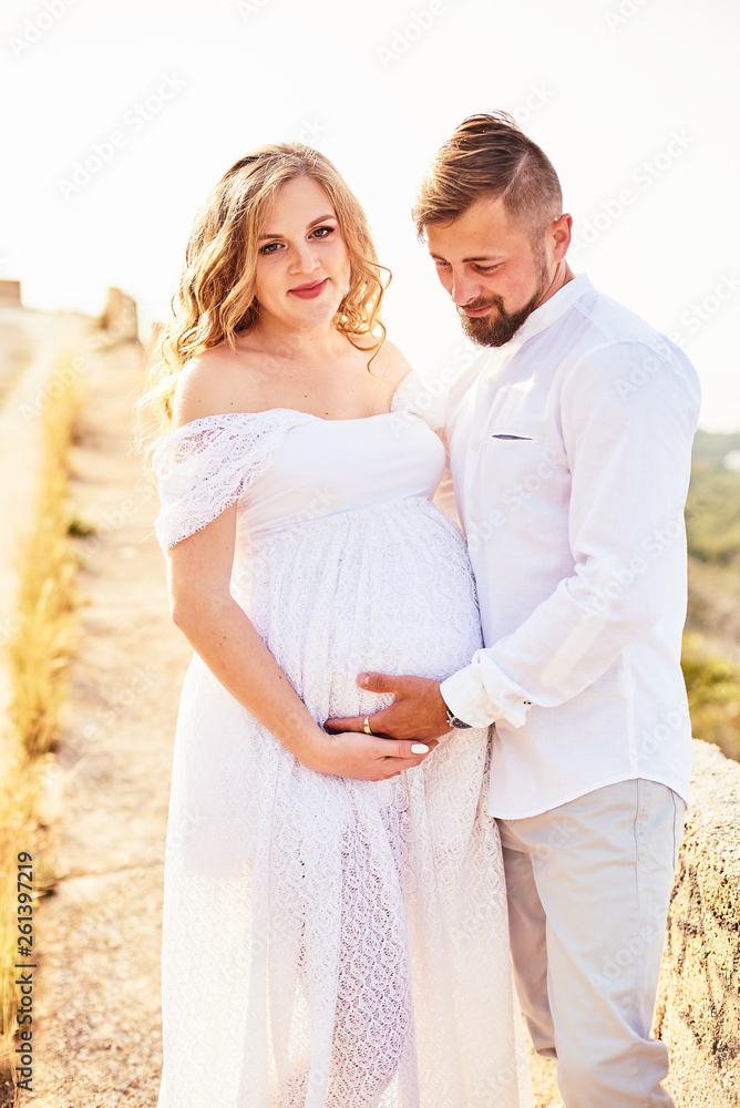 Obraz premium Portrait of a young pregnant woman posing with her husband on a sunny summer day