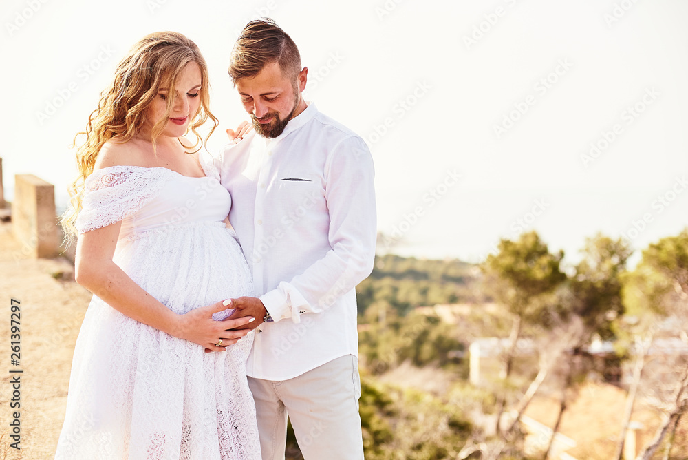 Portrait of a young pregnant woman posing with her husband on a sunny summer day Portrait of a young pregnant woman posing with her husband on a sunny summer day