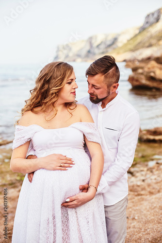 Portrait of a young pregnant woman posing with her husband on a sunny summer day