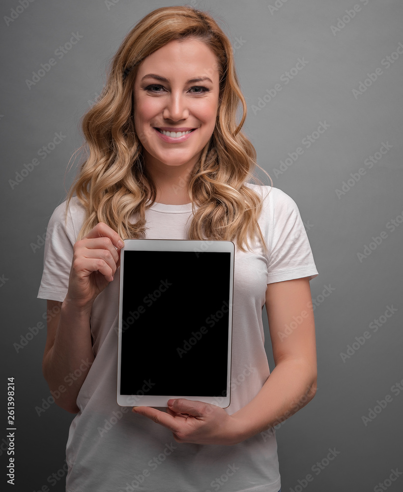 Attractive blonde is holding tablet pc on a gray background. Attractive blonde is holding tablet pc on a gray background.
