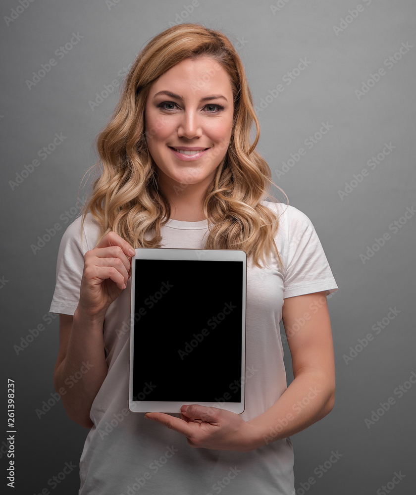 Attractive blonde is holding tablet pc on a gray background. Attractive blonde is holding tablet pc on a gray background.