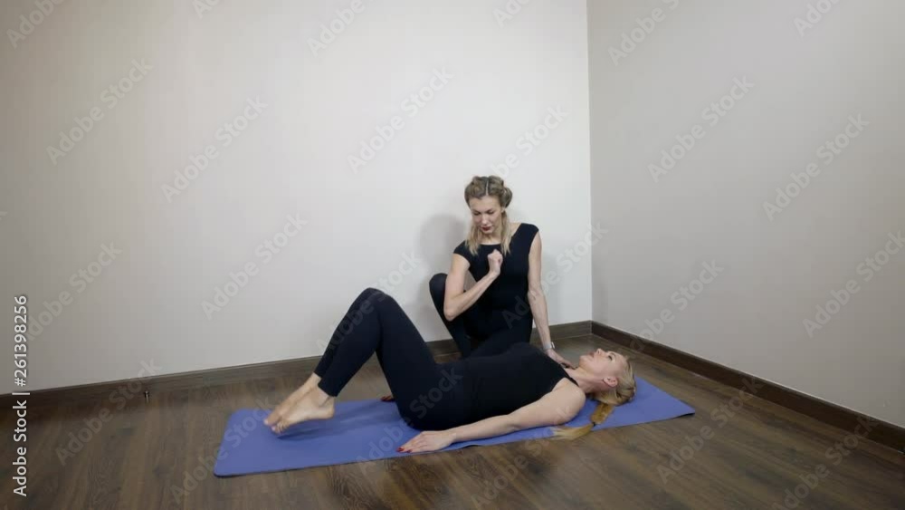 trainer woman is checking body position of young athlete girl making legs lift on floor trainer woman is checking body position of young athlete girl making legs lift on floor