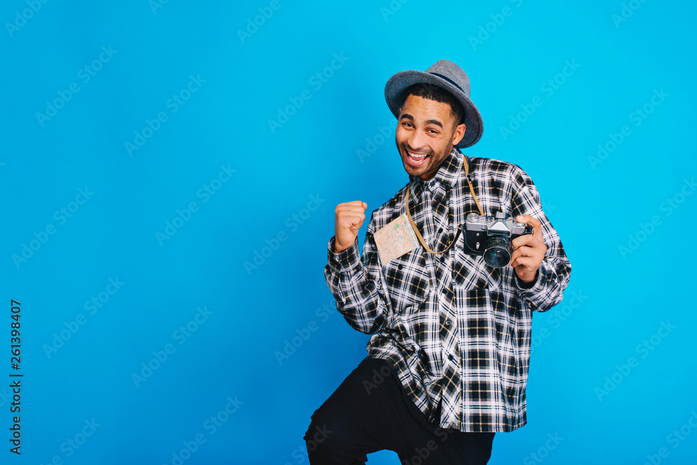 Excited joyful young handsome man expressing positive emotions on blue background. Travelling, tourism, camera, map, cheerful mood, happiness, positivity, jorney, smiling. Place for text Excited joyful young handsome man expressing positive emotions on blue background. Travelling, tourism, camera, map, cheerful mood, happiness, positivity, jorney, smiling. Place for text