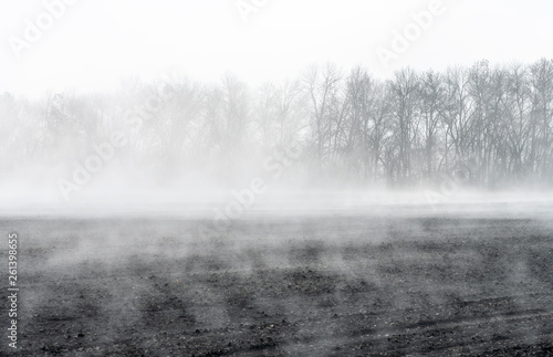 Spring, the evaporation of water from the arable land rises forming a mist over the field photo