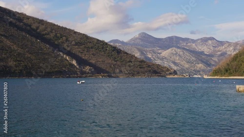 Fisherman on boat catching fish. On background mountains of the Kotor bay photo