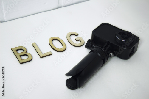 Concept on the topic of Blogger. Action Camera with wooden letters on a white background.