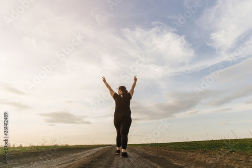 Body positive, freedom, high self esteem, confidence, happiness, inspiration, success, positive affirmation. Overweight woman celebrating rising hands to the sky on summer meadow. © Vadym