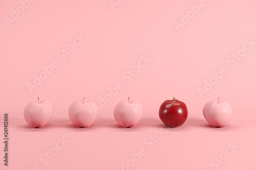 Outstanding red apple among pink painted apples on pastel pink background. Minimal fruit idea concept.