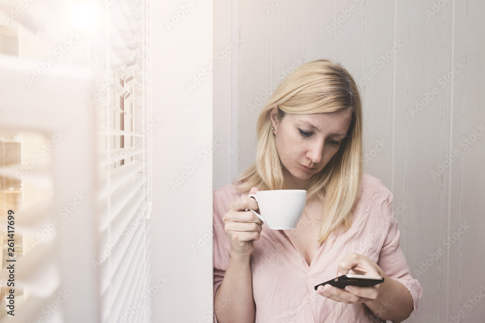 Business woman drinking coffee in the morning sun and using smartphone Business woman drinking coffee in the morning sun and using smartphone