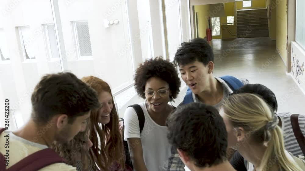 Medium shot of college students stacking hands together while standing in college corridor Medium shot of college students stacking hands together while standing in college corridor