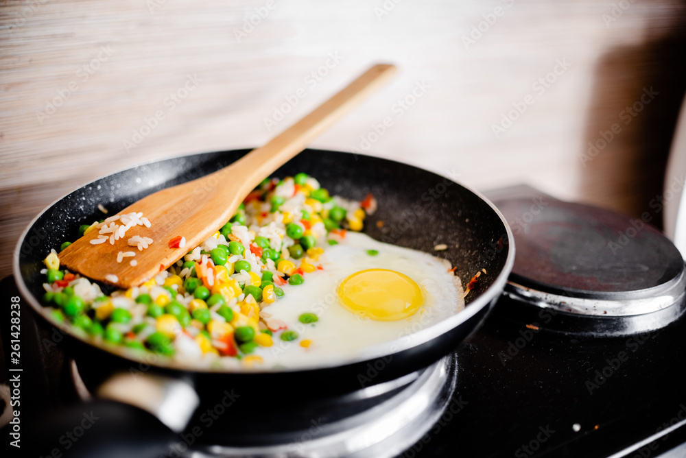 Fried frozen vegetable with rice and fried egg. Food remains in a black frying pan Fried frozen vegetable with rice and fried egg. Food remains in a black frying pan