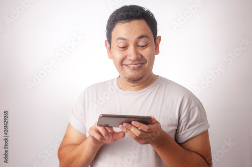 Funny Young Asian Guy Playing Games on Tablet Smart Phone © airdone