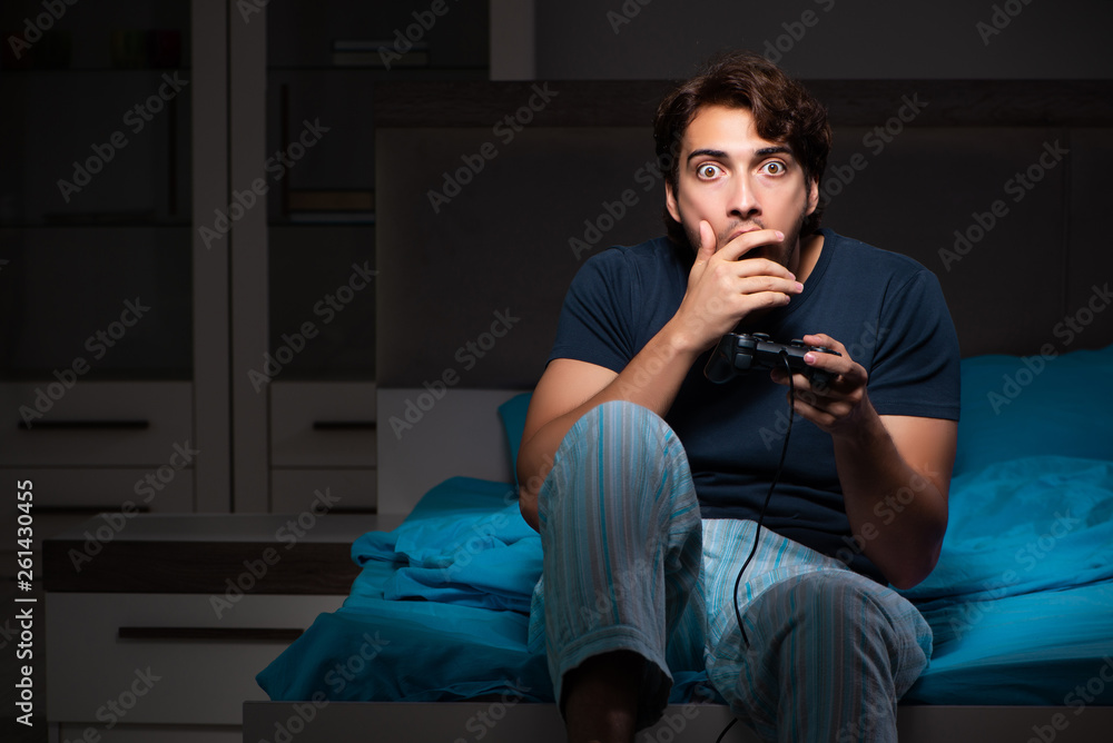 Young man playing computer games at night in bed Young man playing computer games at night in bed