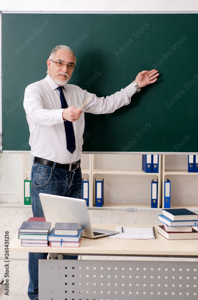 Aged male teacher in front of chalkboard Aged male teacher in front of chalkboard