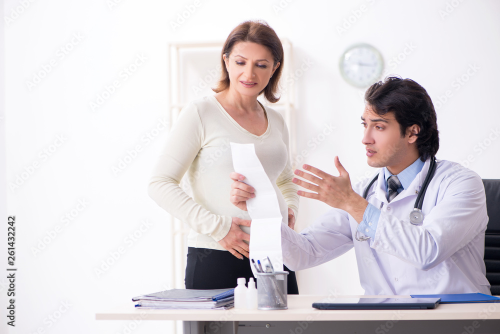 Old pregnant woman visiting young male doctor Old pregnant woman visiting young male doctor