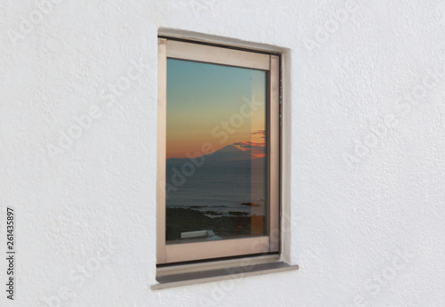 ホテルの白壁の窓に映る富士山の夕焼け空