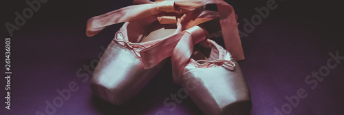 Pointe shoes ballet dance shoes with a bow of ribbons beautifully folded on a dark background.