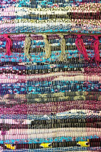Needlework. Textile background with fabric texture with horizontal lines. A rug for home made from colorful patches of old things sewn in rows with fringe