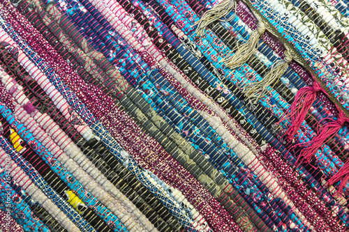 Needlework. Textile fabric background with diagonal lines. A rug for home made from colorful patches of old things sewn in rows with fringe