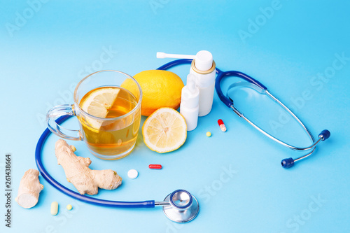 Cold preparations, stethoscope, tea, lemon and ginger root on a blue background. photo