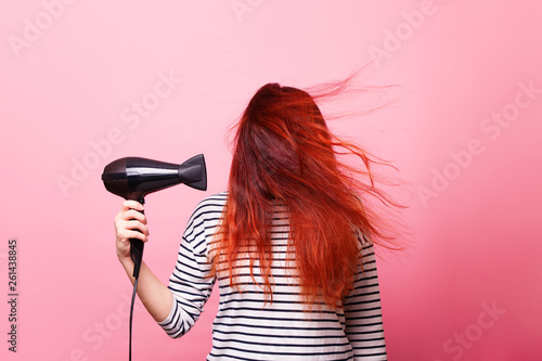 Woman holding a hairdryer on a pink background