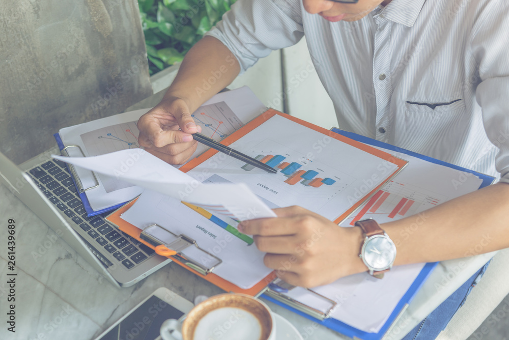 Office man holding pen and checking financial report Office man holding pen and checking financial report