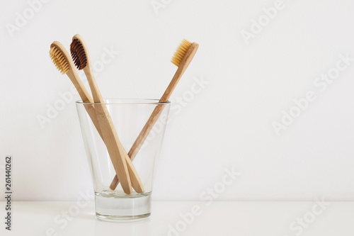 set of natural toothbrushes in glass on table in bathroom