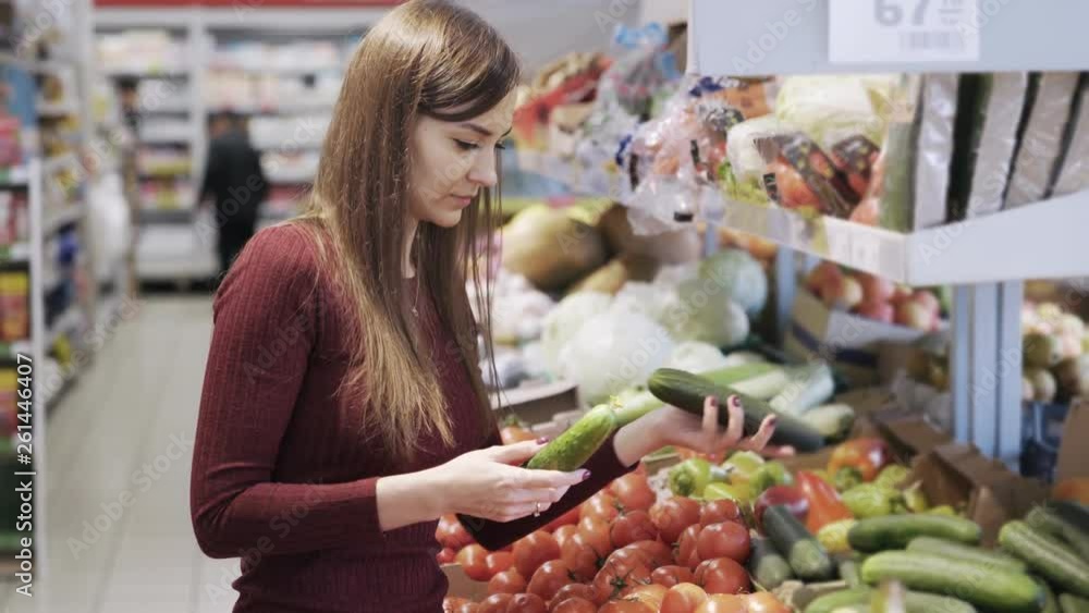 Young girl buys vegetables in grocery department of supermarket and puts them in plastic bag Young girl buys vegetables in grocery department of supermarket and puts them in plastic bag