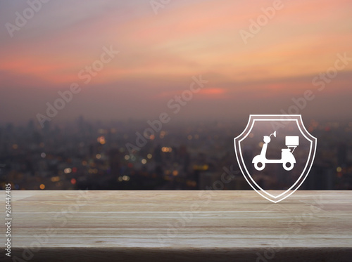 Motorcycle with shield flat icon on wooden table over blur of cityscape on warm light sundown, Business motorbike insurance concept