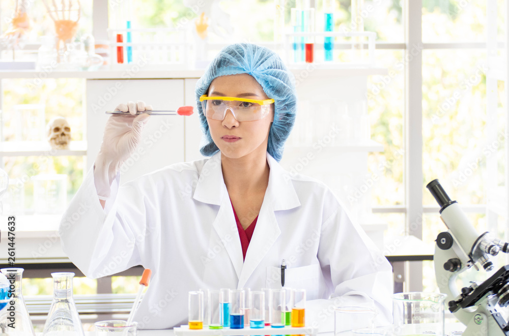 Scientists look at a cotton ball that is attached to a red chemical. Scientists look at a cotton ball that is attached to a red chemical.