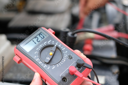 auto mechanic check car battery voltage by voltmeter multimeter photo